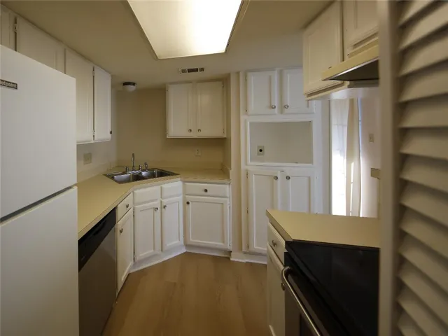 a kitchen with granite countertop a sink cabinets and stainless steel appliances