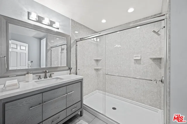 a bathroom with a bathtub shower sink vanity and mirror