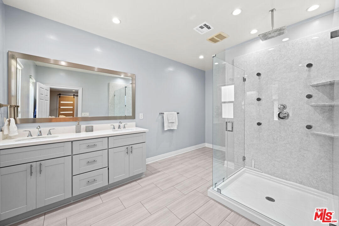 15042 Valleyheart Drive Sherman Oaks, CA 91403 - Photo 18 of 31 a spacious bathroom with a granite countertop sink a mirror a shower and a bathtub