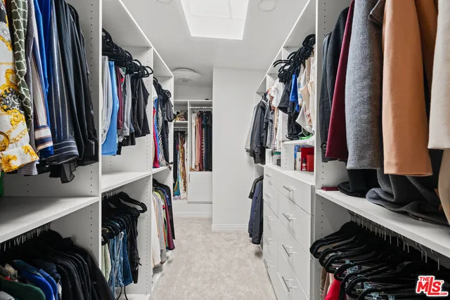 a view of walk in closet with clothes and shoes