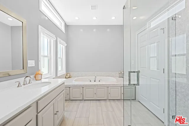 a bathroom with a tub a sink and mirror