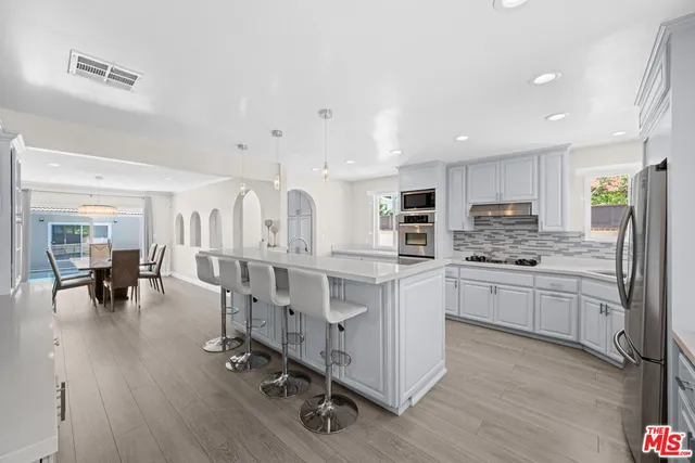 a kitchen with white cabinets sink and chairs