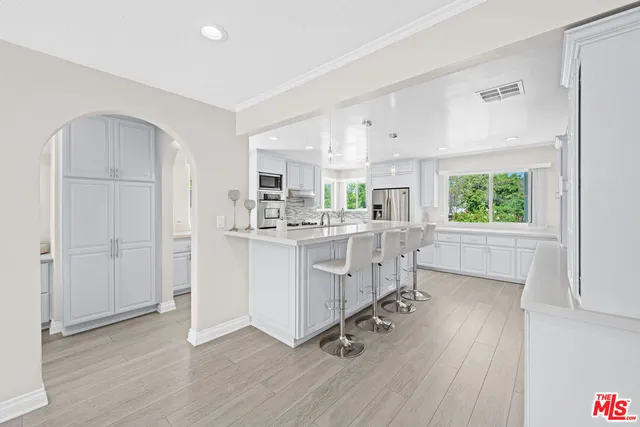 a kitchen with white cabinets and window