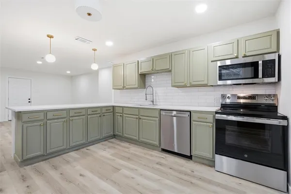 a kitchen with stainless steel appliances granite countertop a stove a sink and a microwave