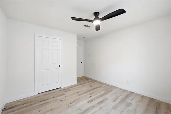 an empty room with wooden floor ceiling fan and windows