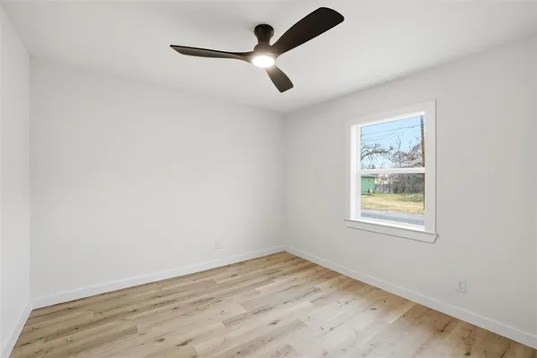 an empty room with a window and a ceiling fan