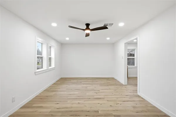 a view of empty room with wooden floor and fan