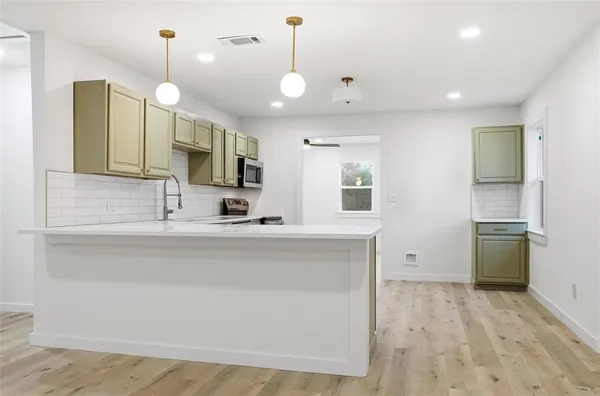 a large kitchen with kitchen island a large counter space a sink appliances and cabinets