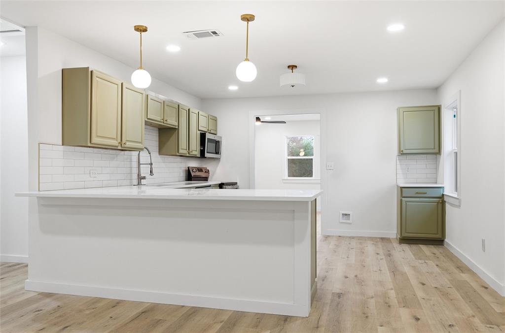 1221 Chestnut Street Waco, TX 76704 - Photo 9 of 32 a large kitchen with kitchen island a large counter space a sink appliances and cabinets
