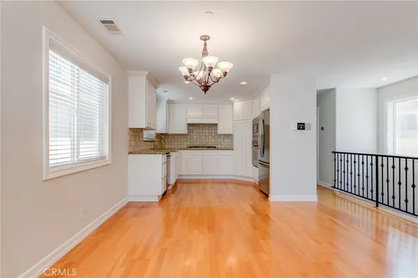 a view of a kitchen with granite countertop wooden floor stainless steel appliances and a window