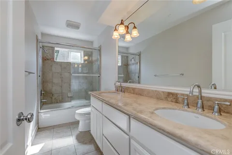 a bathroom with a granite countertop sink a toilet a mirror and bathtub
