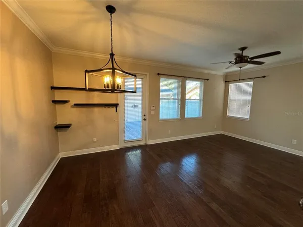 a view of a room with wooden floor ceiling fan and windows