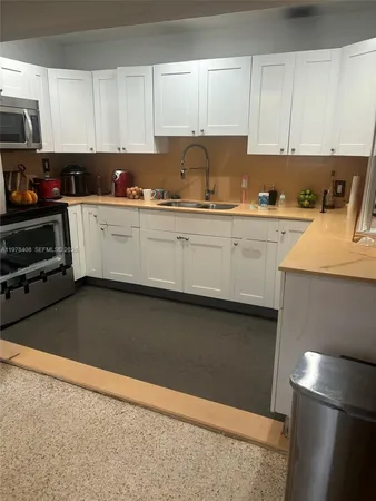a kitchen with granite countertop a sink a stove and cabinets