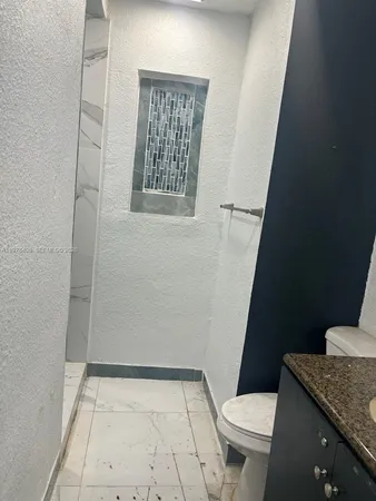 a bathroom with a granite countertop sink and a toilet