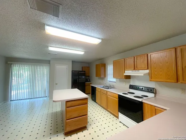 a kitchen with kitchen island granite countertop a stove and a sink