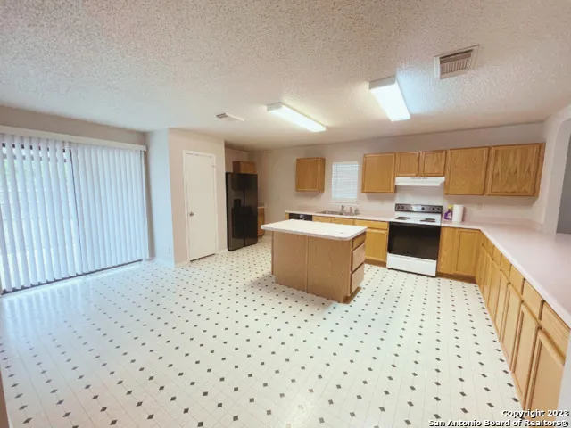 a kitchen with a sink a stove a refrigerator a microwave oven and a dining table with wooden floor