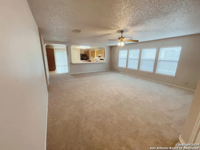 an empty room with windows and ceiling fan