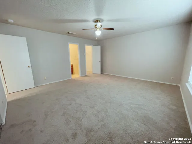 an empty room with a ceiling fan and window
