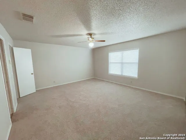 an empty room with windows and ceiling fan
