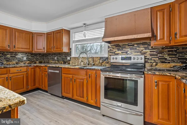 a kitchen with stainless steel appliances granite countertop wooden cabinets a stove and a sink