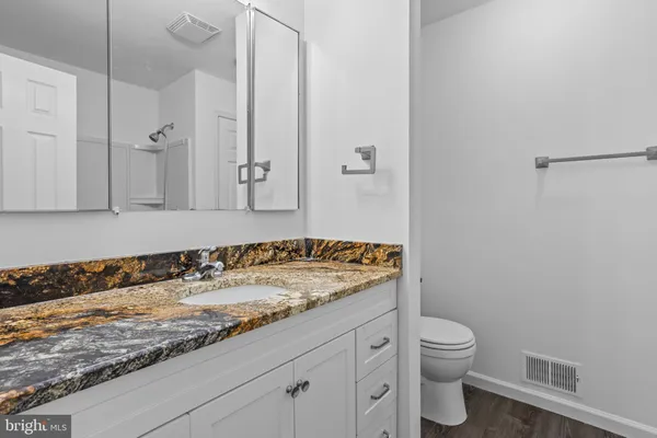 a bathroom with a granite countertop sink a toilet and a shower