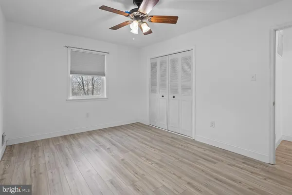 a view of an empty room with chandelier fan and wooden floor