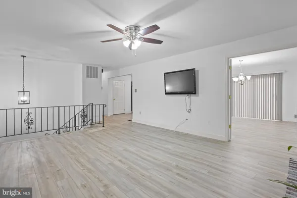 a view of an empty room with wooden floor and a chandelier