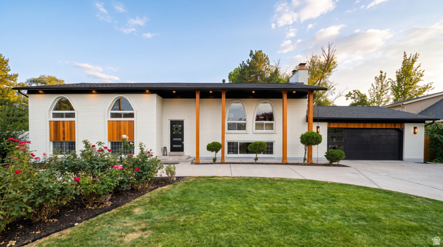 1860 Spring Lane Holladay, UT 84117 - Photo 2 of 32 White brick exterior featuring arched windows, wood accents, an integrated garage, and a concrete driveway