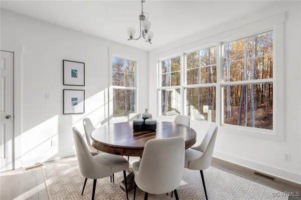 a kitchen with stainless steel appliances a microwave a stove a sink dishwasher a refrigerator and white cabinets with wooden floor