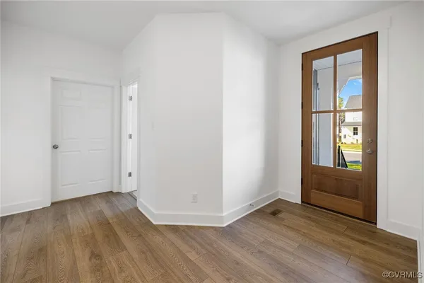 an empty room with wooden floor and windows