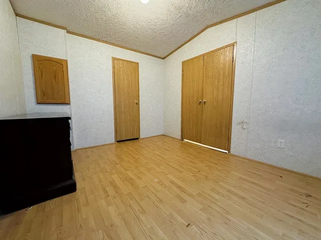 a view of an empty room with wooden floor and closet