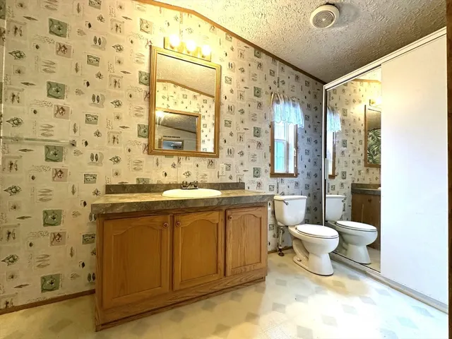 a bathroom with a granite countertop sink toilet a mirror and shower