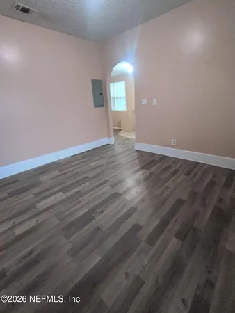 an empty room with wooden floor and windows