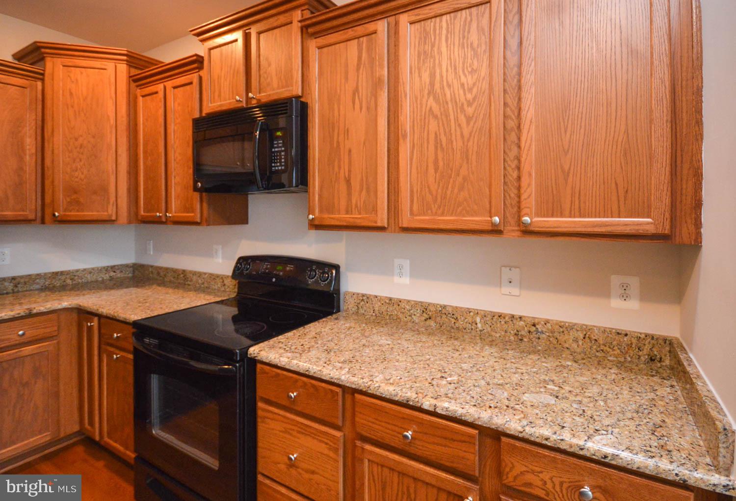 8426 Winding Trail Laurel, MD 20724 - Photo 11 of 41 a kitchen with granite countertop wooden cabinets and a stove top oven