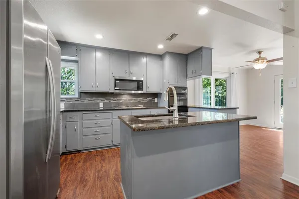 a kitchen with stainless steel appliances granite countertop a sink a stove and a refrigerator