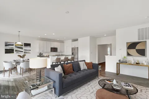 a living room with furniture kitchen view and a chandelier
