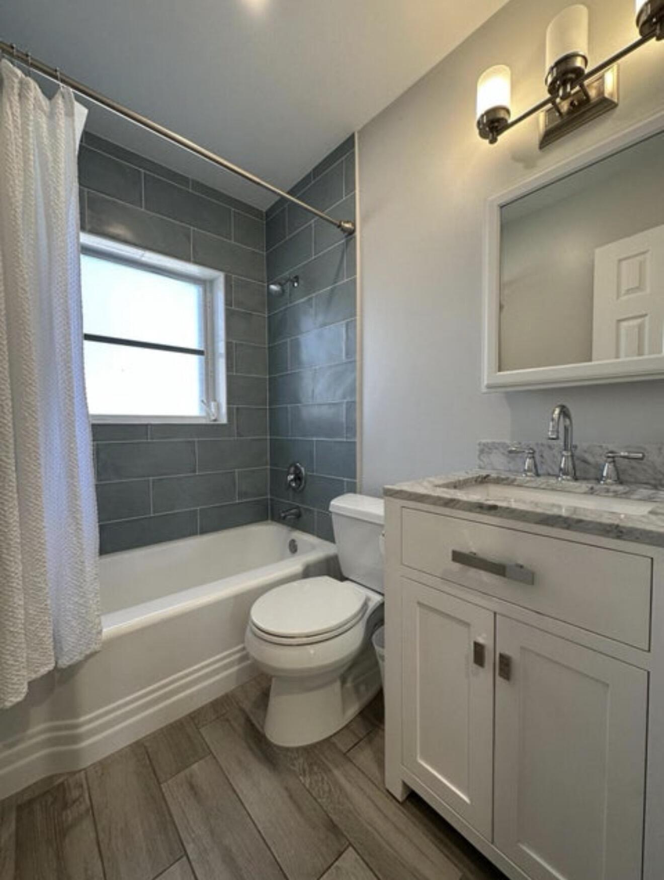 49 Douglas Drive Ocean Ridge, FL 33435 - Photo 38 of 65 a bathroom with a granite countertop sink toilet a mirror and bathtub