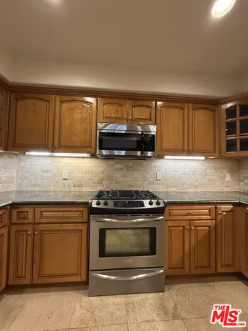 a kitchen with granite countertop a stove top oven cabinets and a window