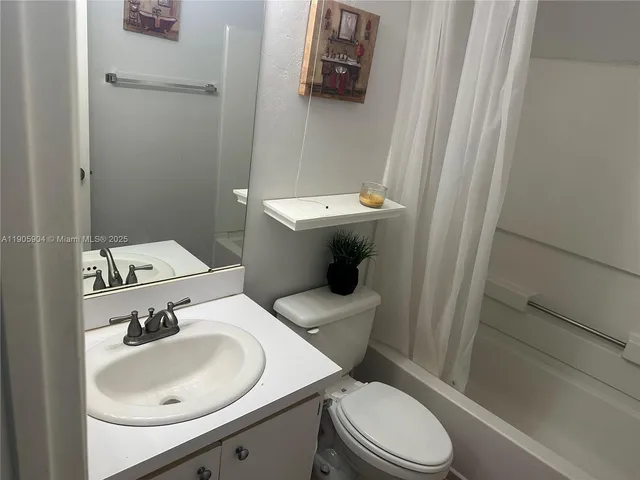 a bathroom with a sink a toilet and shower curtain