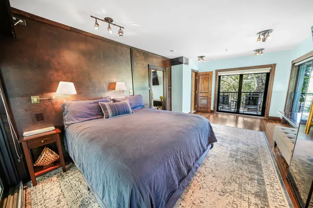 a bedroom with bed and large windows