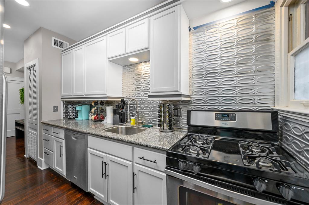 a kitchen with stainless steel appliances granite countertop a stove a sink and white cabinets