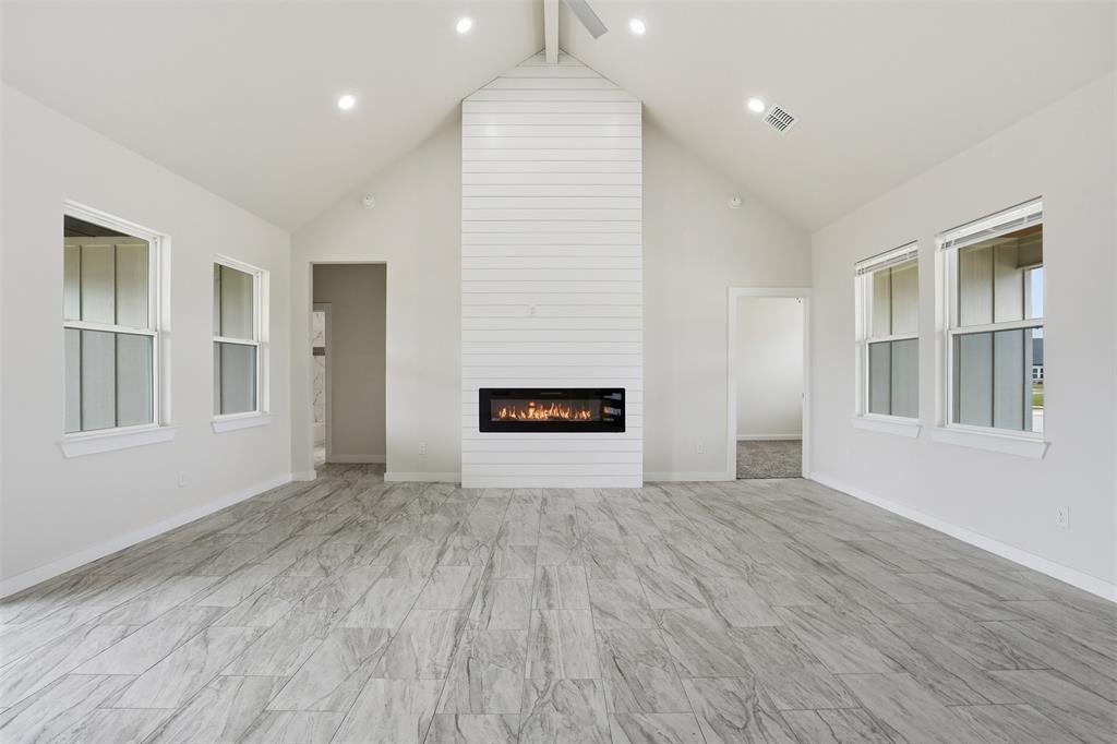 532 Highview Court Godley, TX 76044 - Photo 28 of 39 Spacious living area featuring a vaulted ceiling and a shiplap-clad fireplace with a linear insert