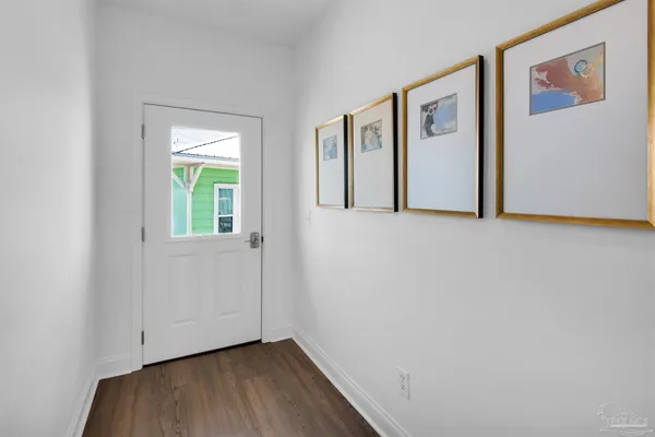 a view of an empty room with window and wooden floor