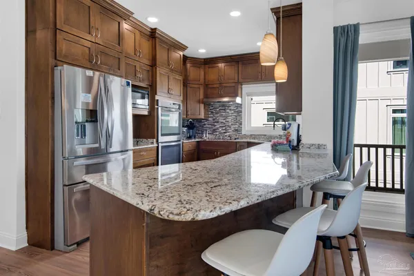 a kitchen with kitchen island granite countertop a table chairs and a refrigerator
