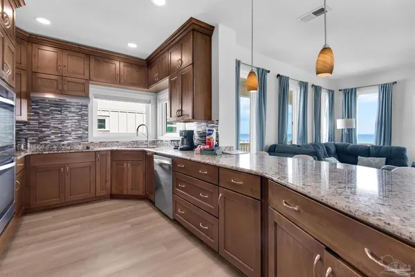 a open kitchen with granite countertop a sink dishwasher a stove and a refrigerator with wooden floor