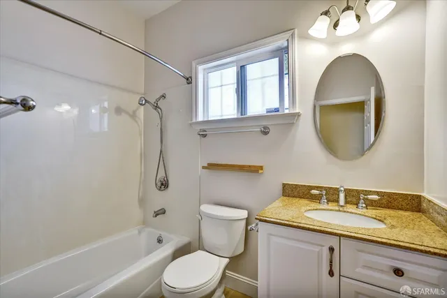 a bathroom with a granite countertop toilet sink and mirror