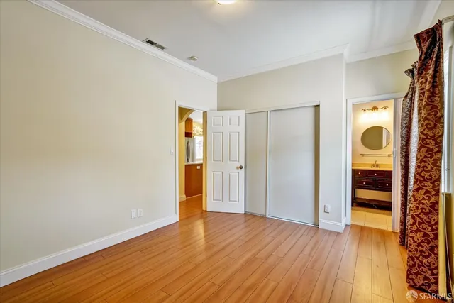 a view of an empty room with wooden floor and closet area
