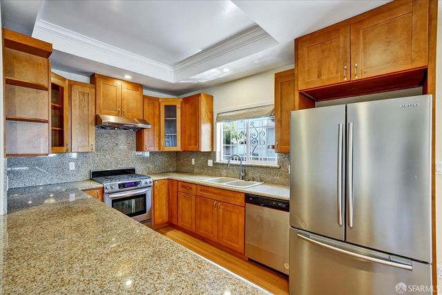 a kitchen with stainless steel appliances granite countertop a refrigerator a sink dishwasher a stove with wooden cabinets and floor