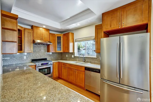 a kitchen with stainless steel appliances granite countertop a refrigerator a sink dishwasher a stove with wooden cabinets and floor