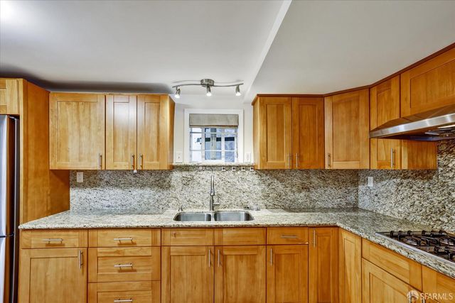 a kitchen with granite countertop wooden cabinets a sink and dishwasher